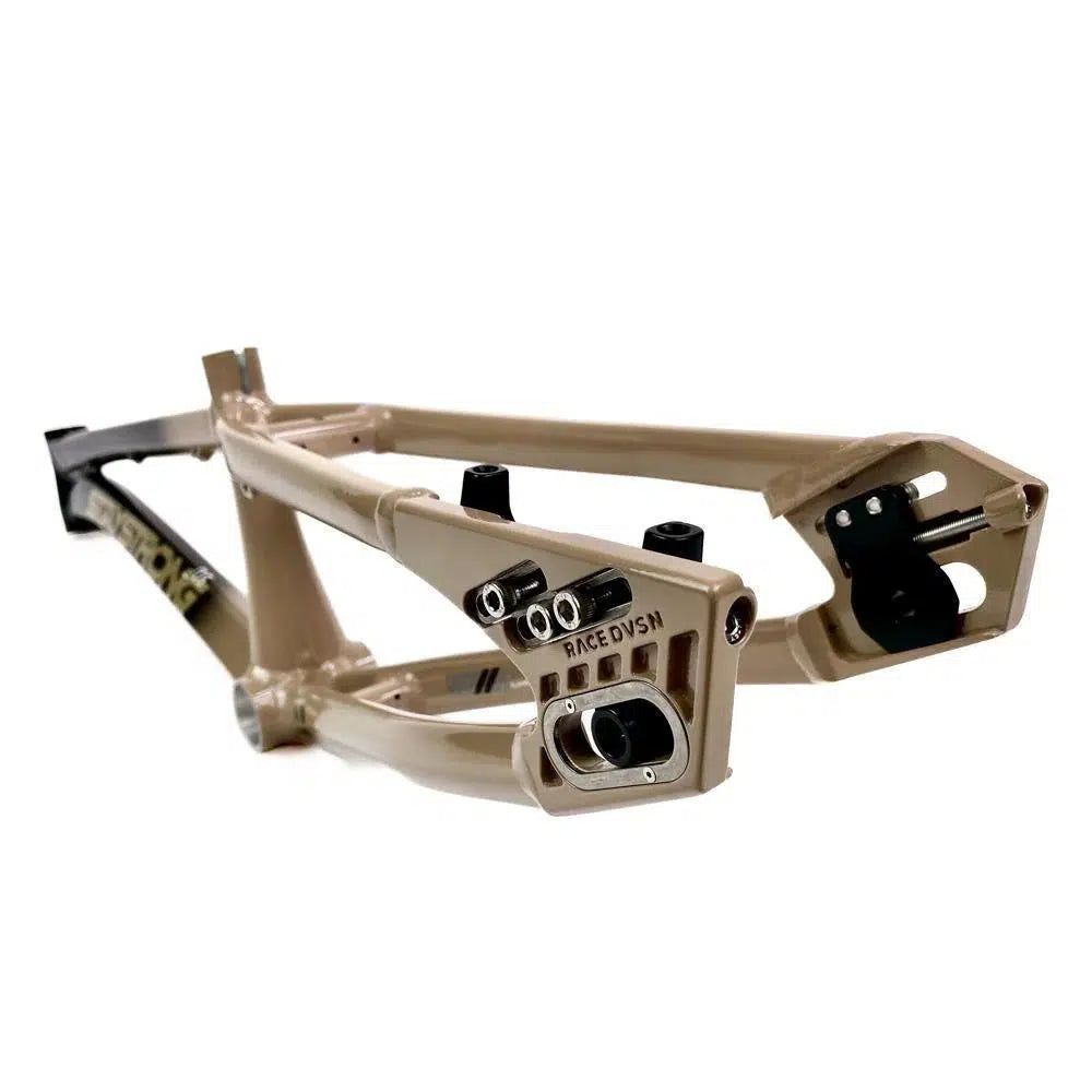 Close-up of a beige-colored aluminium race frame with the brand name "Race Divsn" visible on one section. The Staystrong V5 Disc Pro L Frame, made from 6061 alloy tubing, is angled to showcase its structural design and connection points.