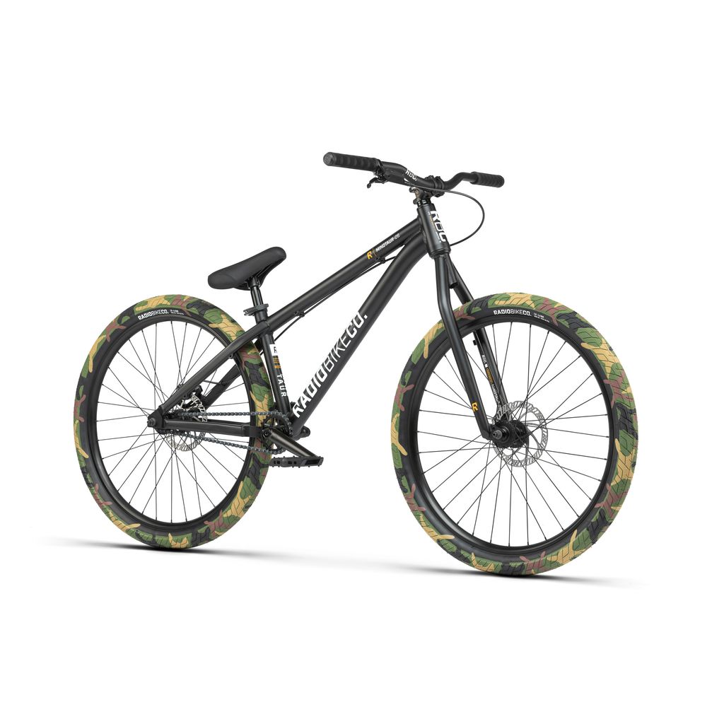 The Radio 26 Inch Minotaur Bike is a black BMX with camouflage-patterned tires, featuring front and rear disc brakes, a flat handlebar, and a rugged 6061-T6 alloy frame—truly a dirt/pump track beast.