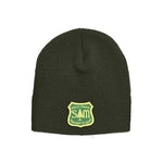 The S&M Department Of Freestyle Beanie is a dark green, knit beanie adorned with a biking patch, featuring a yellow tag that has "S&M Rails Trails Department of Birds" text and a tree silhouette, and is crafted from hypoallergenic acrylic.