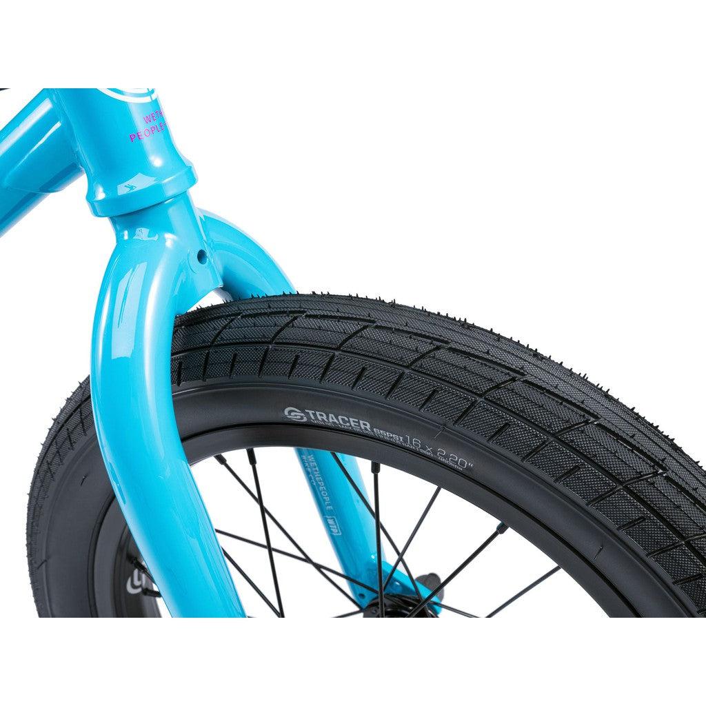 Close-up of the blue bicycle fork and front wheel from the Wethepeople Seed 16 Inch Bike, featuring a black tire with "Tracer" branding and tread pattern—a true BMX shredder.