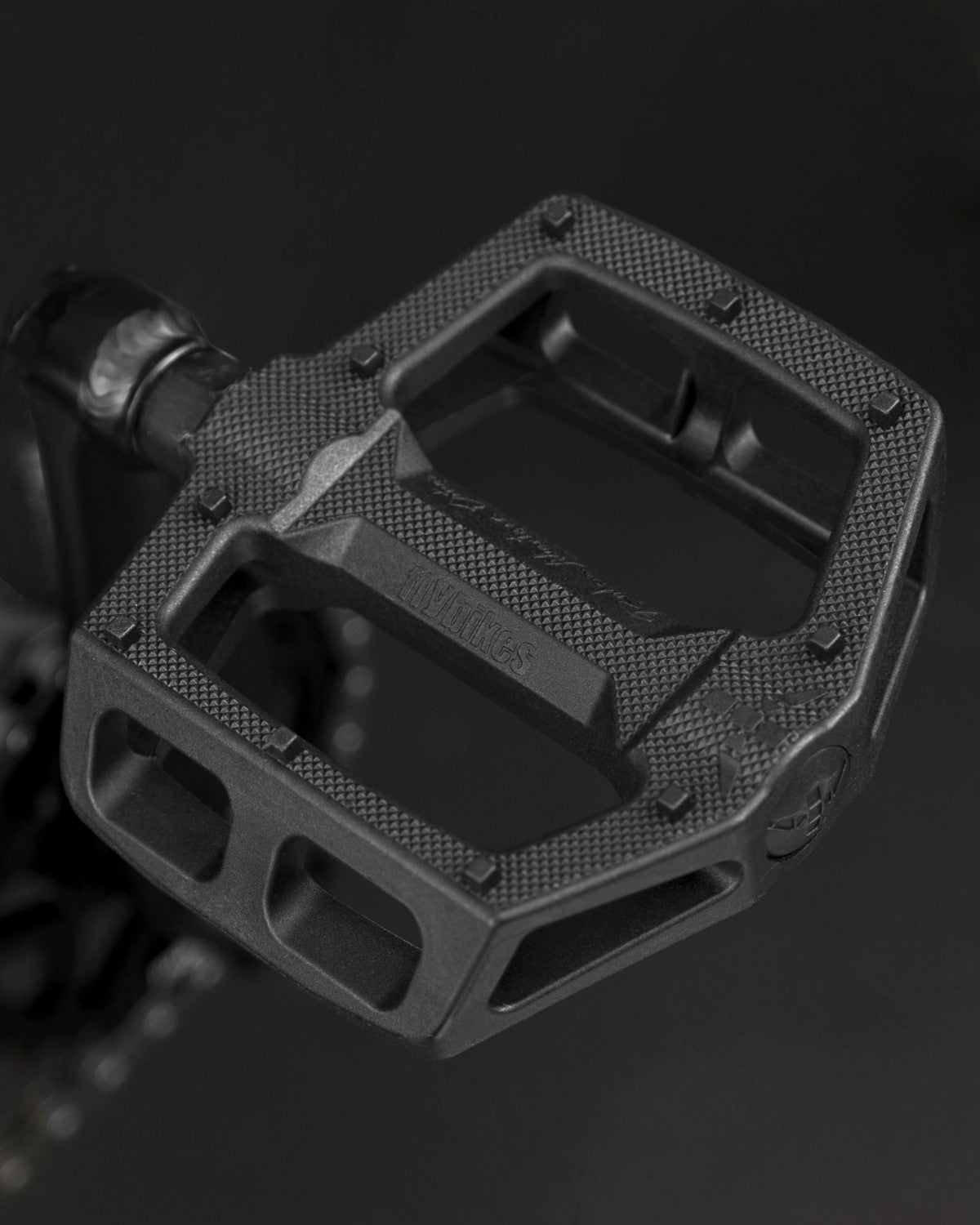 A close-up of a textured black bicycle pedal on a dark background, perfect for your next Fly Bikes Neutron 20 Inch Bike adventure.