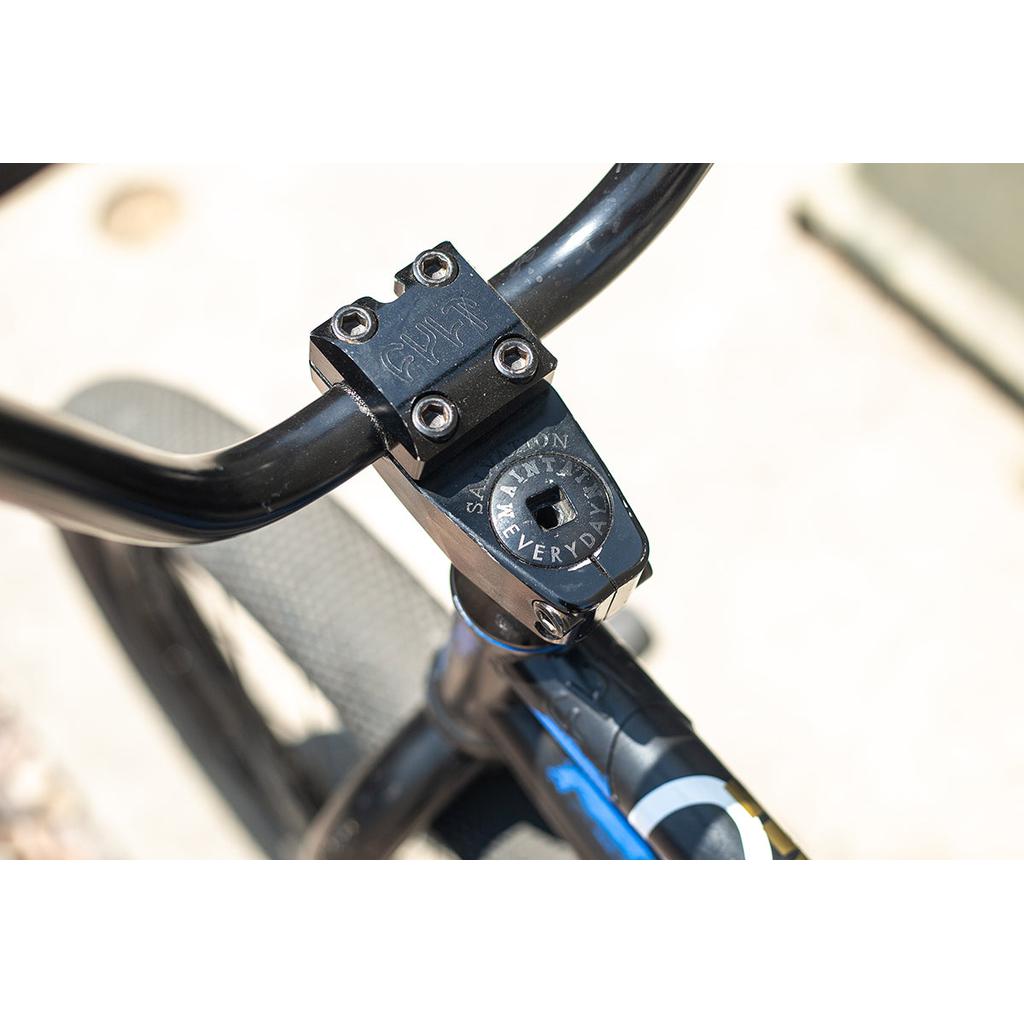 A close-up of the BMX showcases the Cult Salvation V4 Stem, enhancing the setup with an improved clamping area for extra stability. The black stem boldly displays "STAY FLY EVERYDAY," while a sleek blue touch accentuates the partially visible bike frame.