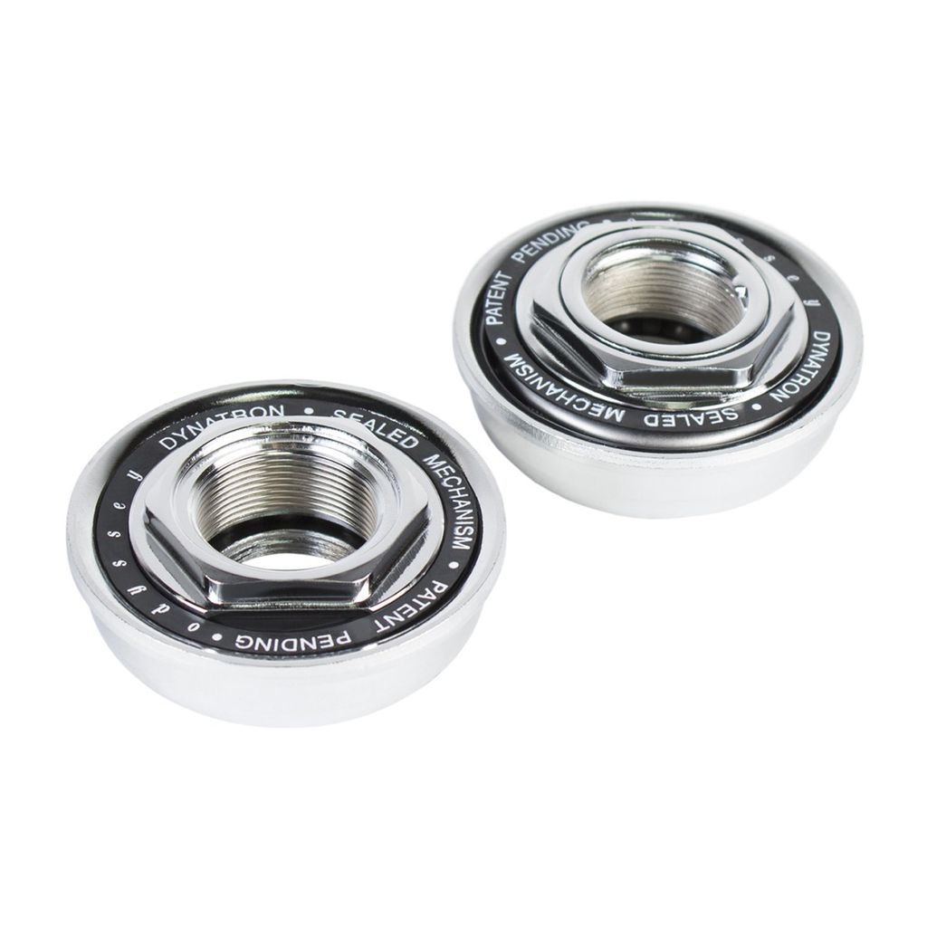 Two metal cylindrical components with engraved text, featuring a threaded opening at the center and labeled "Odyssey Dynatron USA BB Set," resembling Dynatron shields.