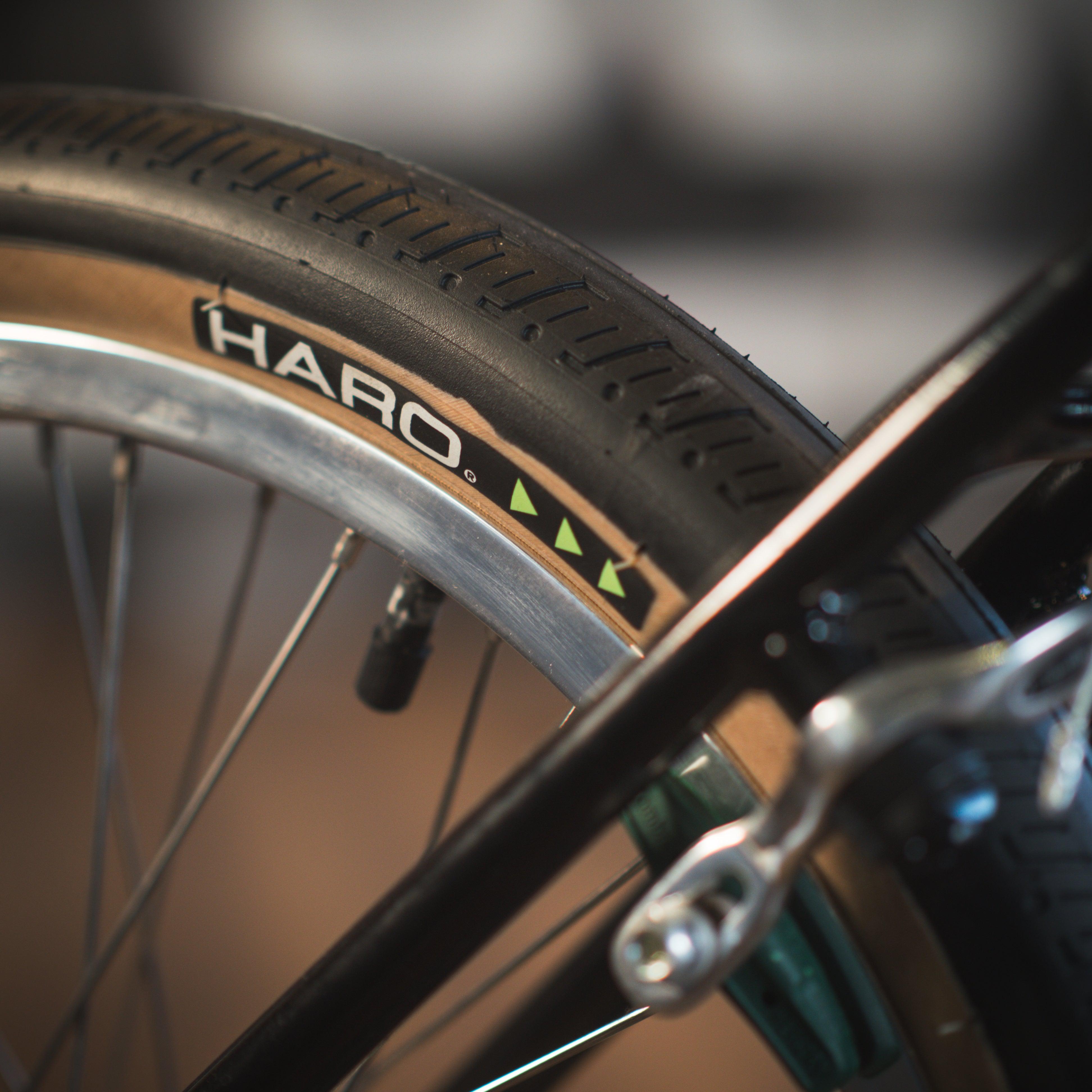 Close-up of a BMX bike tire with the brand name "Haro" visible on the side. The image focuses on the wheel and rim, hinting at its robust frame of the Haro Lineage Sport Freestyler Bashguard 26 Inch Bike.