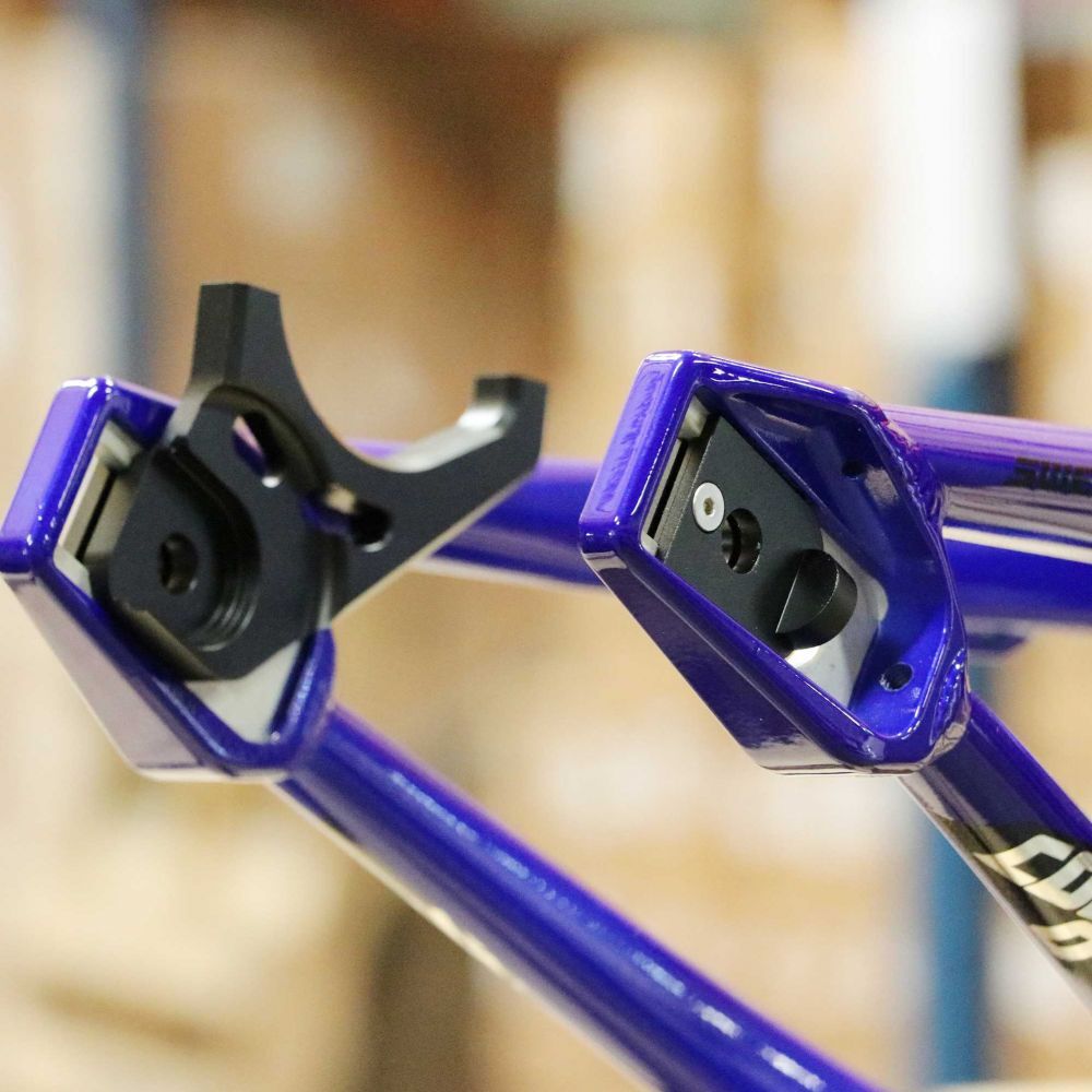 Close-up of the dropouts on a purple bicycle frame, featuring precise alignment for the rear wheel assembly and a Pride S2G Inspyre Disc Mount Kit for ultimate performance.