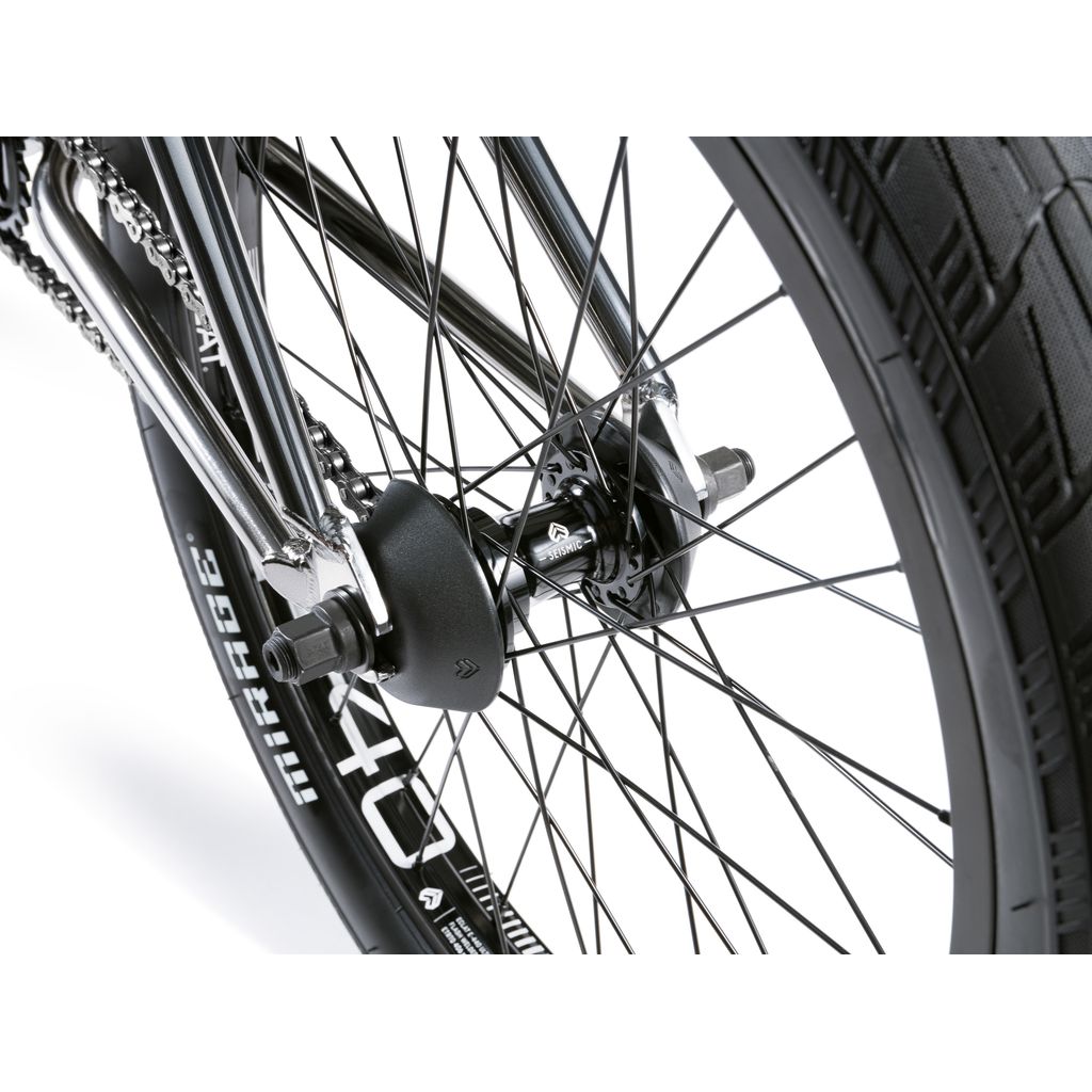 A close-up of the Wethepeople Envy 20 Inch BMX Bike's rear wheel hub showcases black spokes and tire, emphasizing the precision-crafted hub and drivetrain housed in its Chromoly frame.