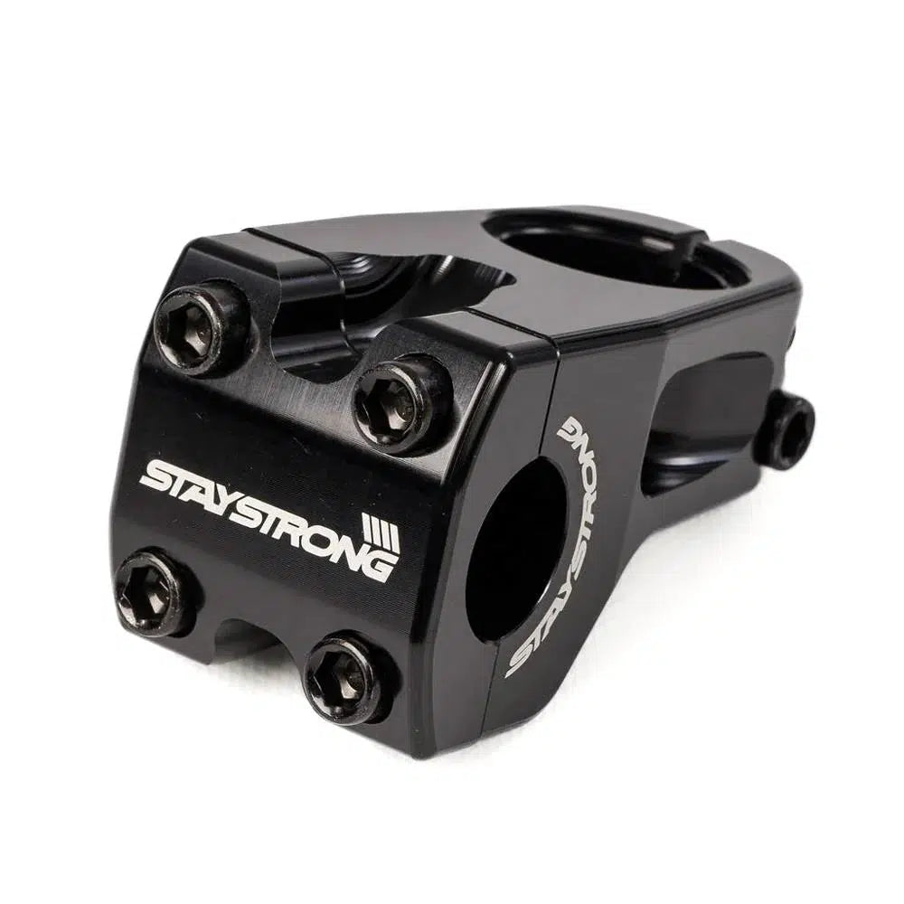 Close-up of a black BMX race stem, CNC'd for precision, with the brand name "STAYSTRONG" printed in white on the front. This Staystrong Front Line V2 Race Stem 1.1/8in model features four bolts at the front for secure attachment.