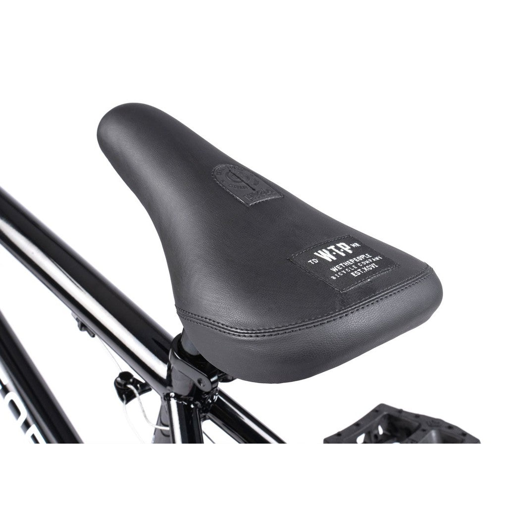 Close-up of a black bicycle seat with visible stitching and label, attached to the Wethepeople CRS FS 18 Inch BMX Bike frame.