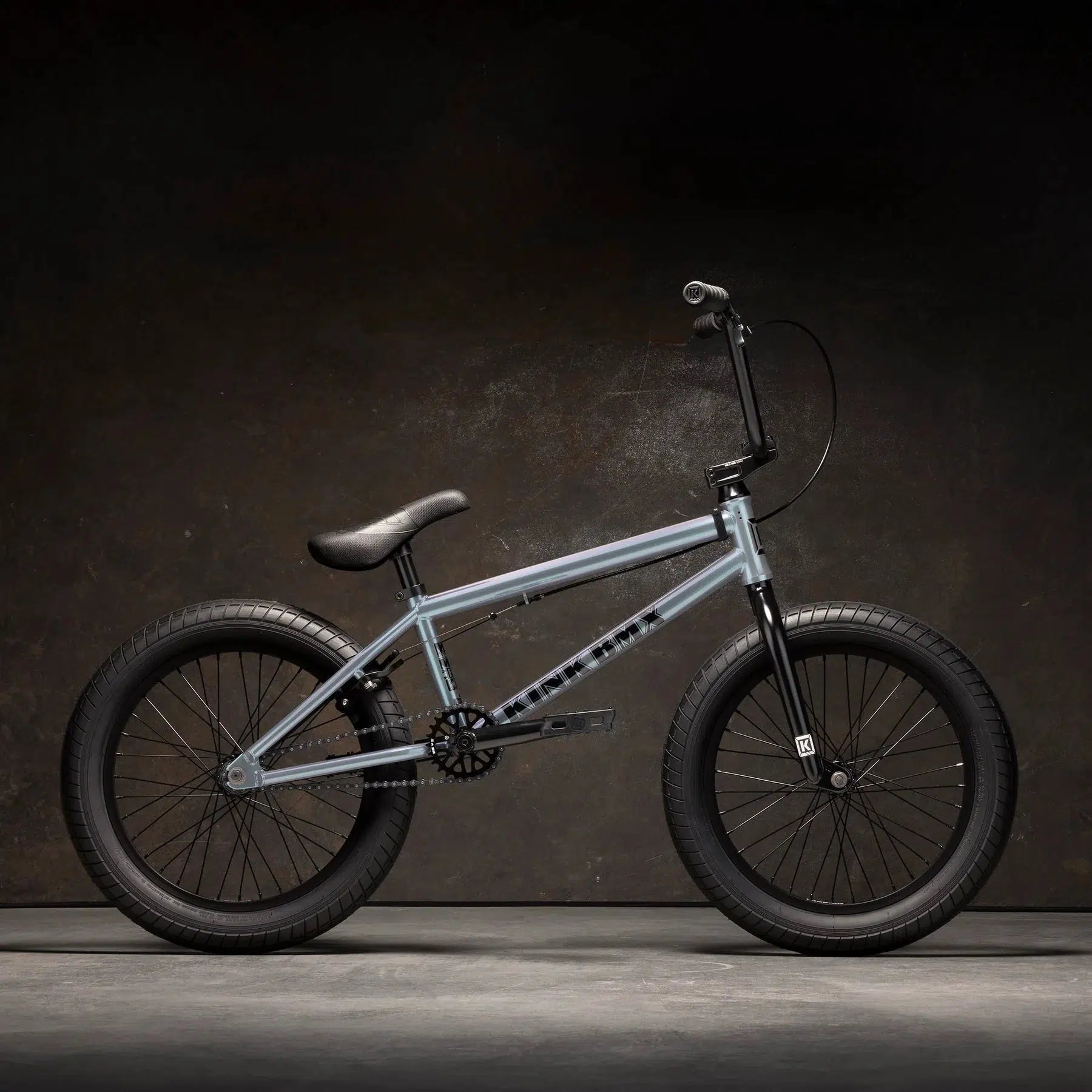 The Kink Kicker 18 Inch Bike, featuring a sleek silver frame complemented by black handlebars, seat, and tires, is showcased against a dark background. This bike is an ideal choice for younger riders eager to dive into the sport of BMX riding.