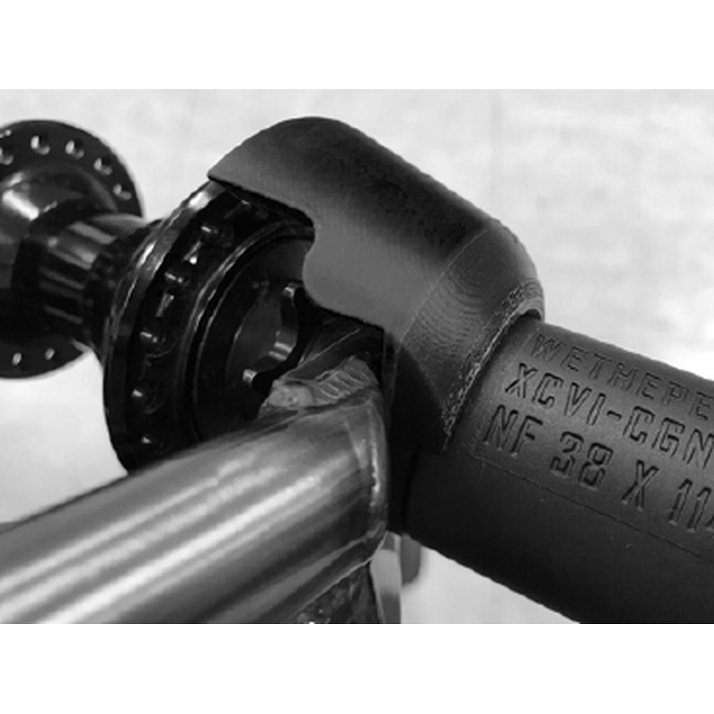 Close-up of a mechanical component featuring a pipe fitting with engraved text, a joint, and a bearing, incorporating elements of an anti-rotation system using Nylon/Fiberglass material from the Eclat Overguard Universal Rear Hub Nylon Guard.