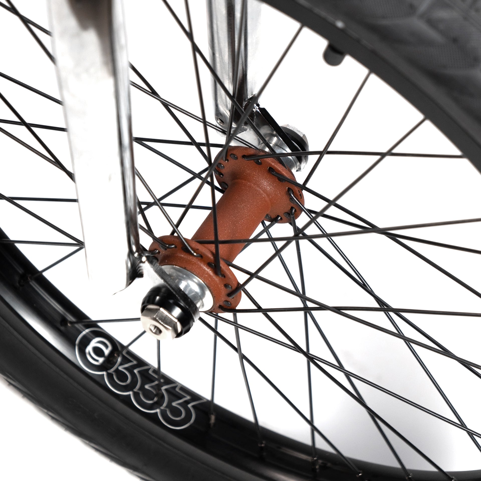 Close-up view of a bicycle wheel's hub and spokes, showcasing a rusty red hub, black spokes, and part of the tire with the number 6333 on the rim. This bike features components from the Wethepeople X LUX LAB 'Ironhide' Chaos Machine 20 Inch Custom Bike for added durability.