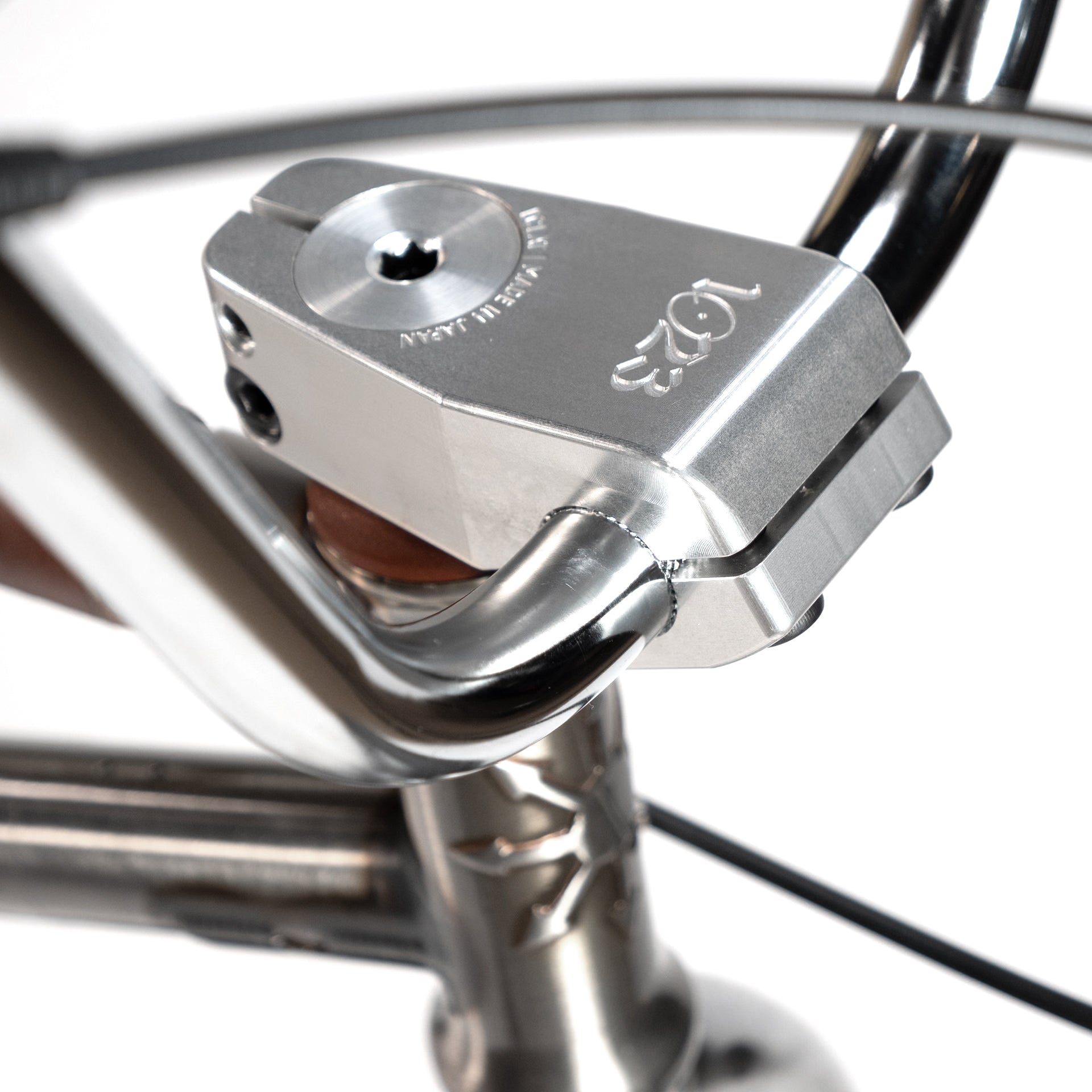 Close-up of a silver bike handlebar lock mechanism attached to the Wethepeople X LUX LAB 'Ironhide' Chaos Machine 20 Inch Custom Bike, with engraved text visible on the lock.