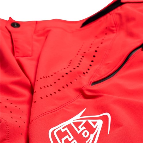 Close-up of the TLD 25.1 Sprint Pant (Youth) in Fiery Red, featuring ventilation perforations, a zippered pocket, and a geometric white logo reminiscent of Troy Lee's designs.