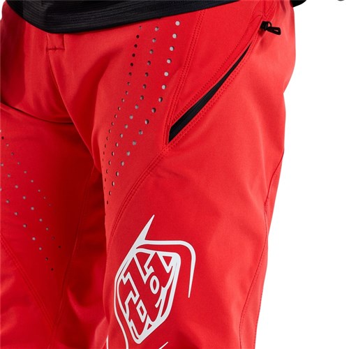 Check out the detailed close-up of the race-ready TLD 25.1 Sprint Pant in Mono Fiery Red, featuring perforated detailing, a white logo, and a convenient zippered pocket, all crafted from durable materials.