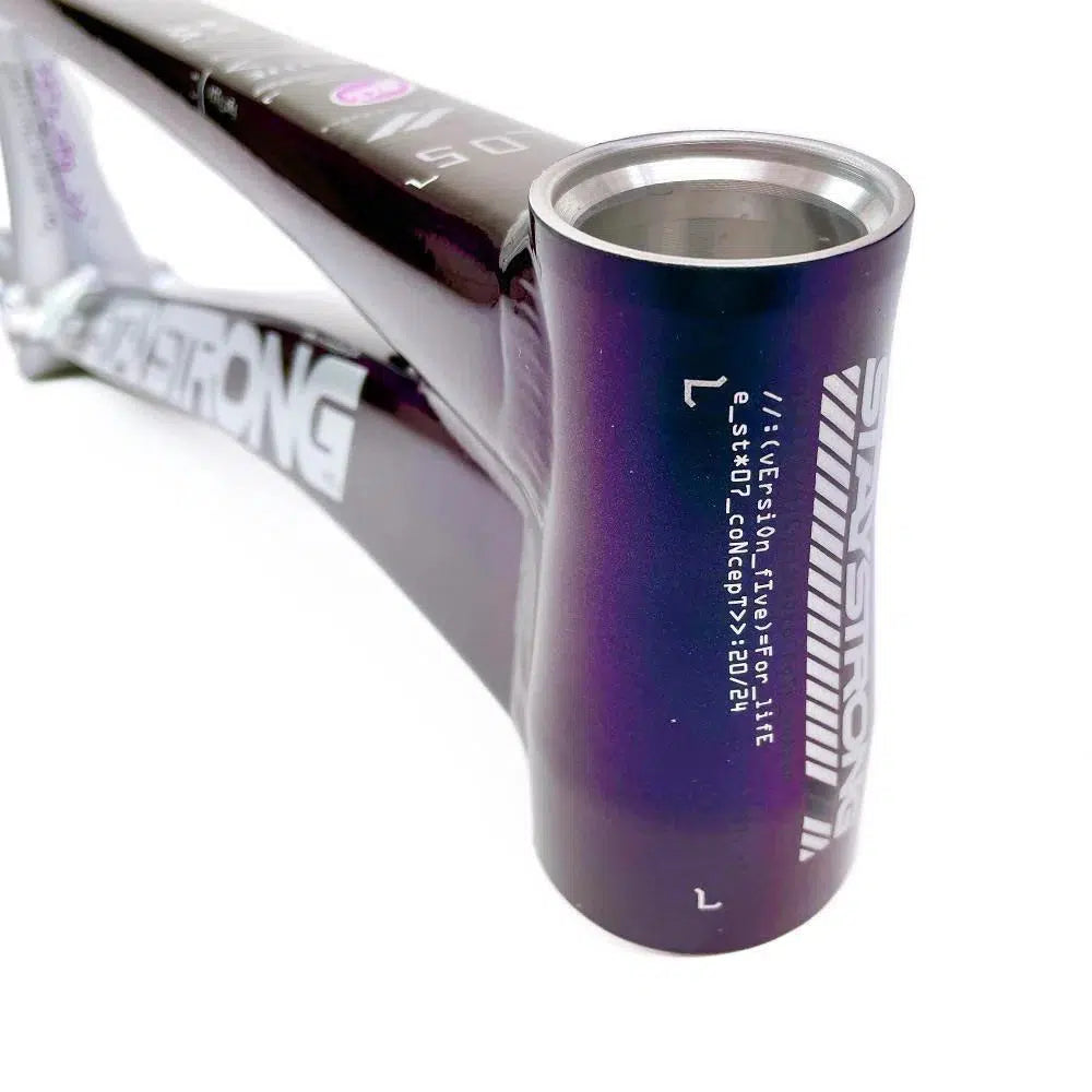 Close-up of a purple bicycle frame with the brand name "Strong" printed on the head tube, and additional text and markings visible on the 6061 alloy tubing. This aluminium race frame is known for its durability, encouraging riders to "Staystrong V5 Disc Pro XXXL Frame".