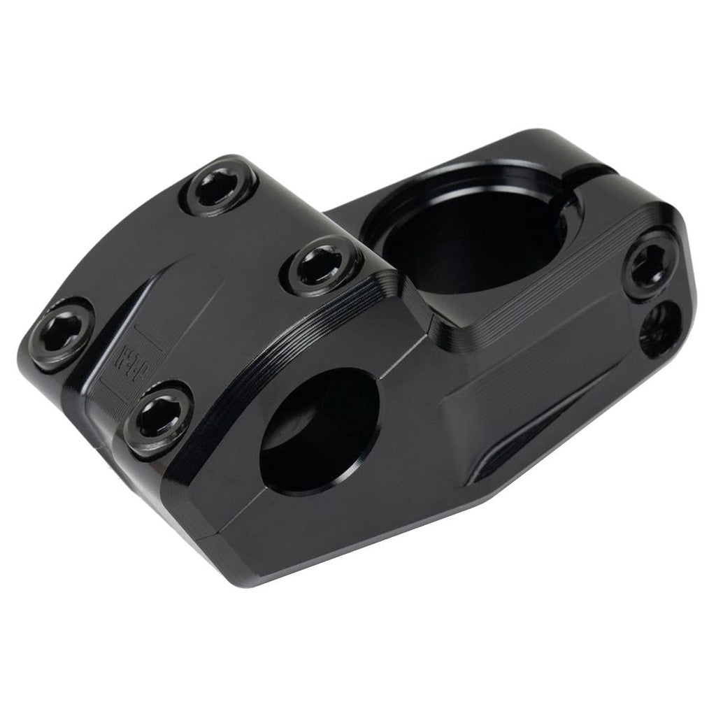 The Wethepeople Kira Top Load Stem, in black metal, features Shark Tooth Clamping and multiple bolts with two circular openings for handlebar and fork attachment. This Flatland Stem enhances grip and stability during freestyle rides.