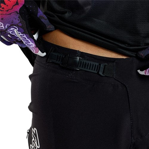 Close-up of a person wearing TLD 25.1 Sprint Ultra Pant / Mono Black with an adjustable buckle for a precise fit, made from Bluesign-approved fabric, perfectly complementing a purple and black patterned top.