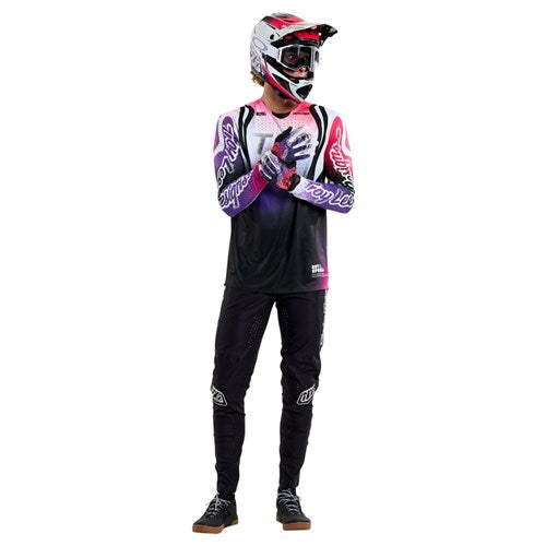 Wearing a colorful motocross outfit, including gloves, and TLD 25.1 Sprint Ultra Pant/Mono Black made from Bluesign-approved fabric for an eco-friendly choice, a person stands against a plain white background.