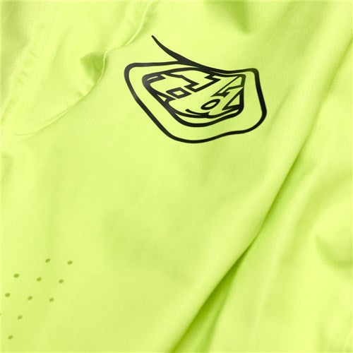 Close-up of the neon yellow TLD 25.1 Sprint Ultra Pant / Mono Glow Yellow with a black geometric logo, crafted from Bluesign-approved fabric for sustainability and a Precision Fit.