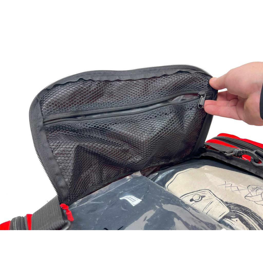 A hand opens a mesh pocket inside the Profile Racing Custom Team Gear Bag in black and red, revealing folded clothing and a transparent plastic bag. Made from durable 600D polyester, this bag balances practicality with style.