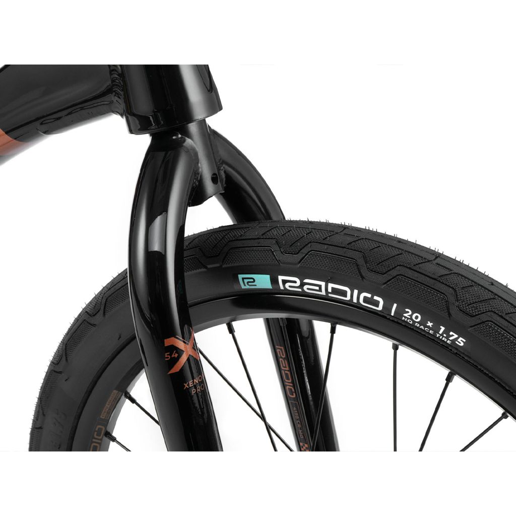 Close-up image of a bicycle front wheel, showing a black tire with white and green branding, labeled "Radio" and "20 x 1.75", part of the high-performance Radio Xenon Pro Bike with durable chromoly forks.