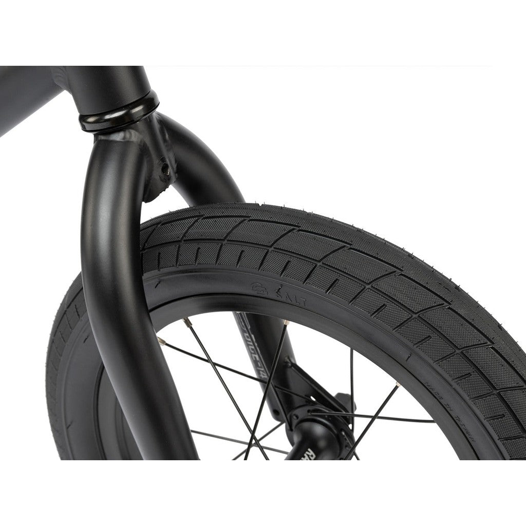 Close-up of a black Radio Dice 14 Inch Bike's front wheel and fork, highlighting the thick tread of the tire and spokes connected to the hub, crafted from a durable 6061-T6 alloy frame.