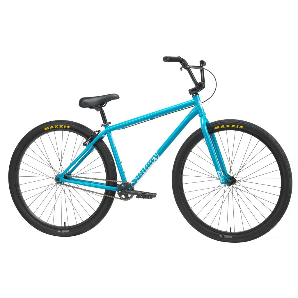 The Sunday High C 29-inch blue BMX bike showcases black handlebars, seat, and tires. It prominently displays "SE BIKES" branding on its durable chromoly frame and "MAXXIS" branding on the tires.