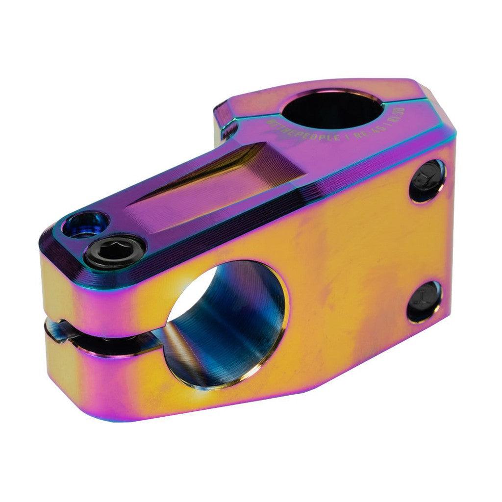 The Wethepeople Kira Top Load Stem features a vibrant metallic gradient with purple, blue, and gold tones, complemented by black screws and shark tooth clamping for a secure grip.