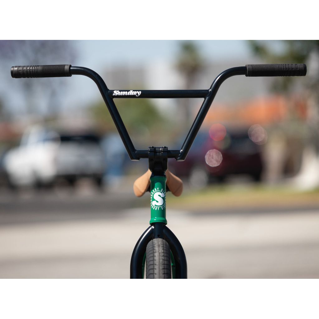 Close-up view of the handlebars and stem of a green Sunday Forecaster 20 Inch Bike (2022) / Alec Siemon with the brand "Sunday" visible, featuring a 100% chromoly frame.