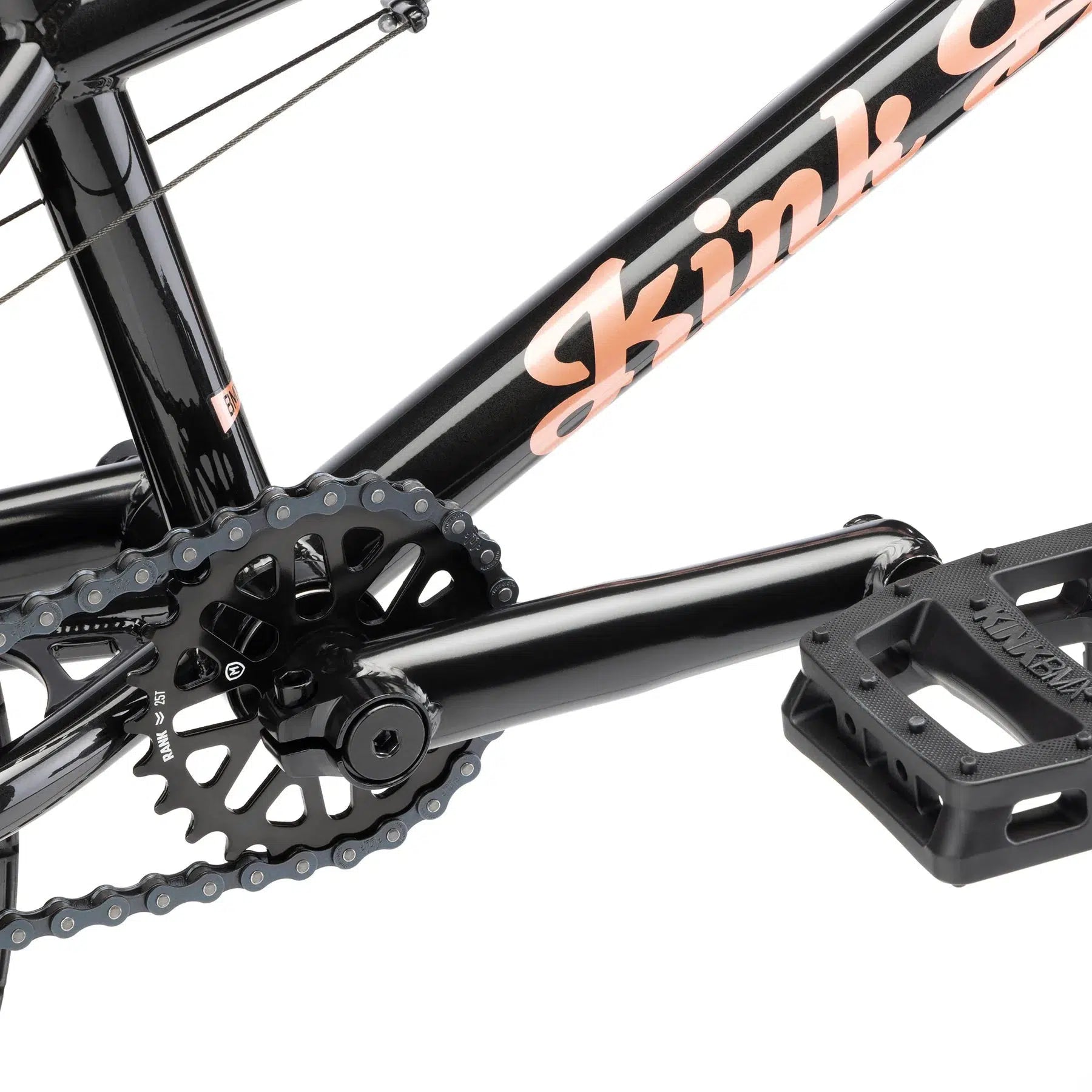 Close-up of the drivetrain on a black BMX bike, featuring the chain, chainring, pedal, and crank arm. The Kink brand logo is prominently displayed on the frame, identifying it as the Kink Carve 16 Inch Bike.