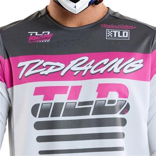 Dressed in the TLD 25.1 Sprint Jersey / Fifty-50 Chalk featuring "Troy Lee Designs" and "TLD" logos, a person prepares for exciting race weekends.