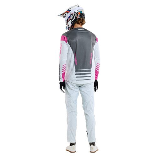 Seen from behind, someone wears a TLD 25.1 Sprint Jersey in Fifty-50 Chalk colors of gray, pink, and white with a helmet—ideal for those exciting race weekends.