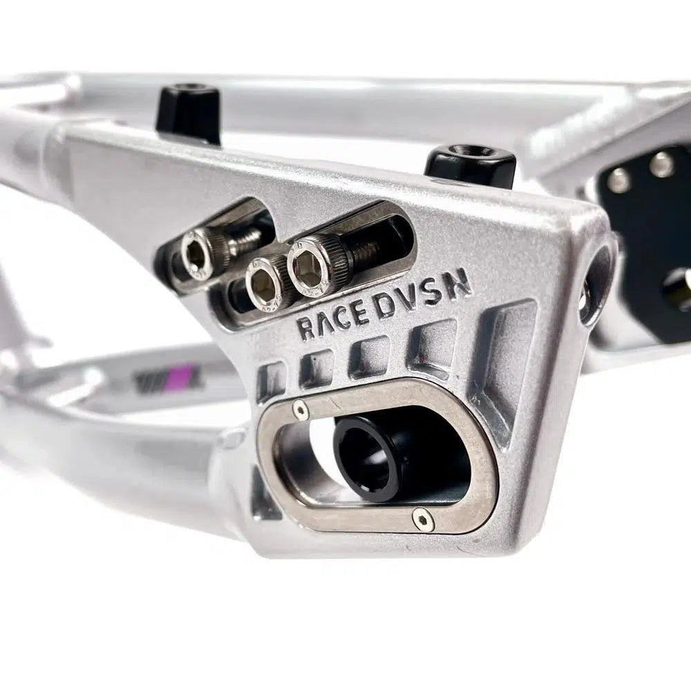 Close-up of an aluminium Staystrong V5 Disc Pro XXXL Frame with the engraving "RACE DVSN" and multiple screws. The part appears to be a section of a mechanical or automotive system.