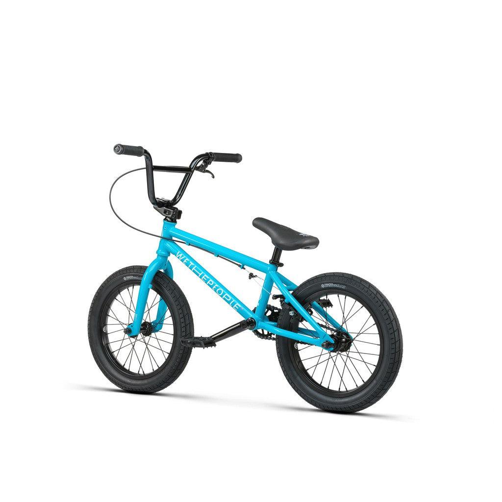 The Wethepeople Seed 16 Inch Bike is a small blue BMX designed for shredding, featuring black handlebars, seat, and tires. It includes durable Salt Rookie cranks and is displayed on a pristine white background.