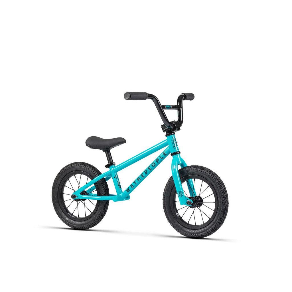 The Wethepeople Prime Balance BMX Bike, a sleek teal children's balance model, features black handlebars, seat, and tires, perfectly showcased on a pristine white background.