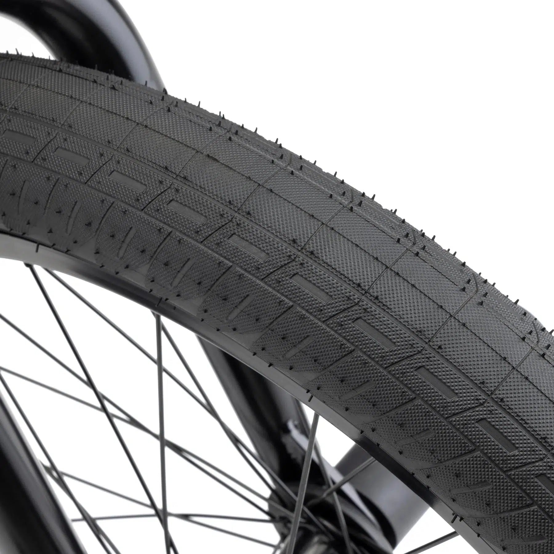 Close-up of a Kink Downside 20 Inch Bike tire with a textured tread pattern and black spokes, showcasing its modern geometry and aftermarket parts.