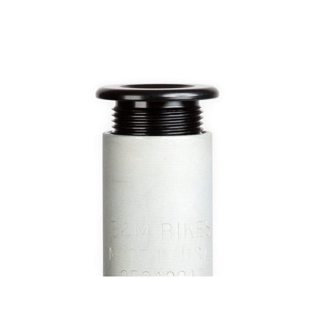 Close-up of a metallic bottle cap with a black top and ribbed neck, evoking the precise engineering typical of S&M Widemouth 20 Inch Forks. The text on the bottle is partially visible but not fully readable.