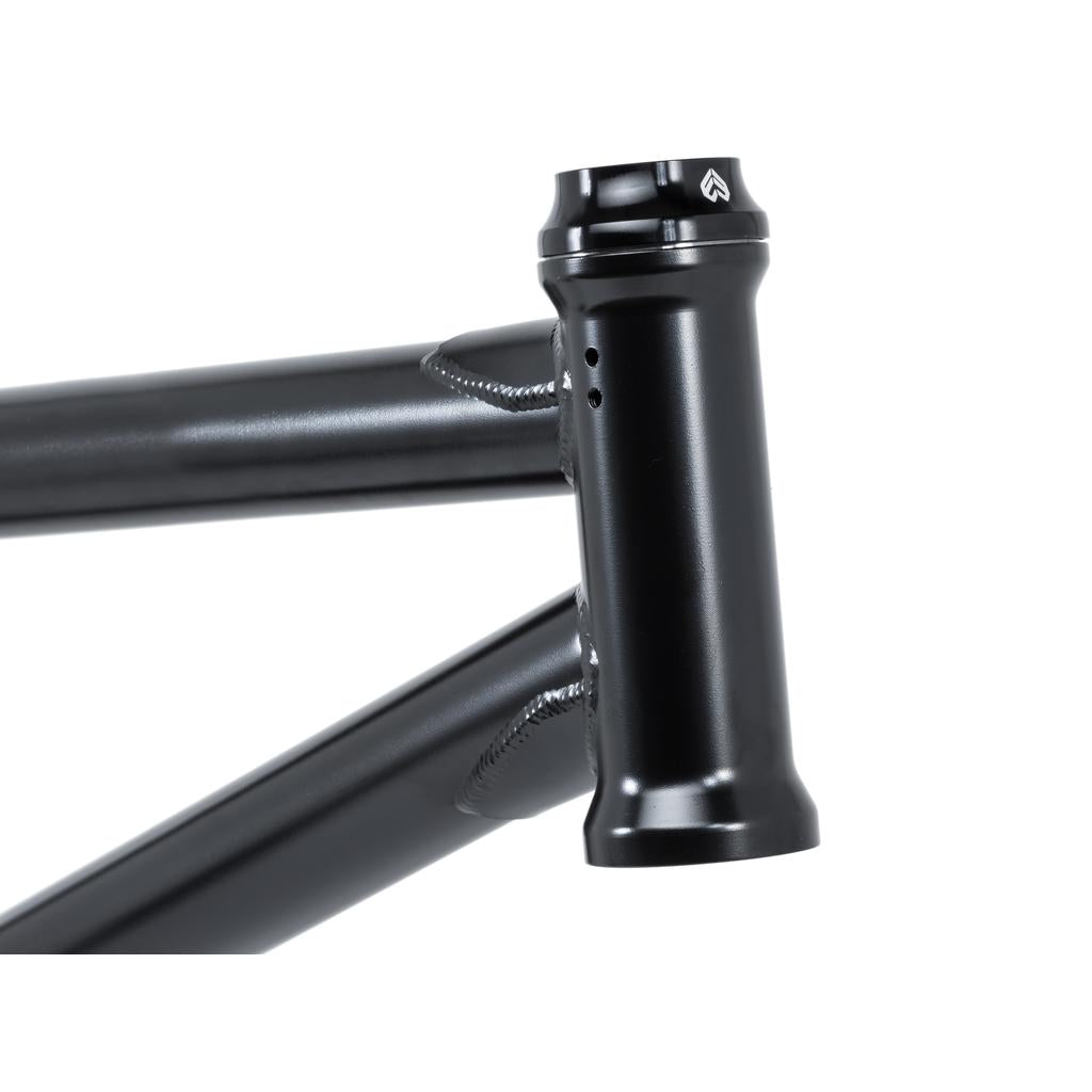 Close-up of a black bicycle frame highlighting the head tube and top tube with evident welds, featuring the sleek Eclat Wave 16mm Headset.