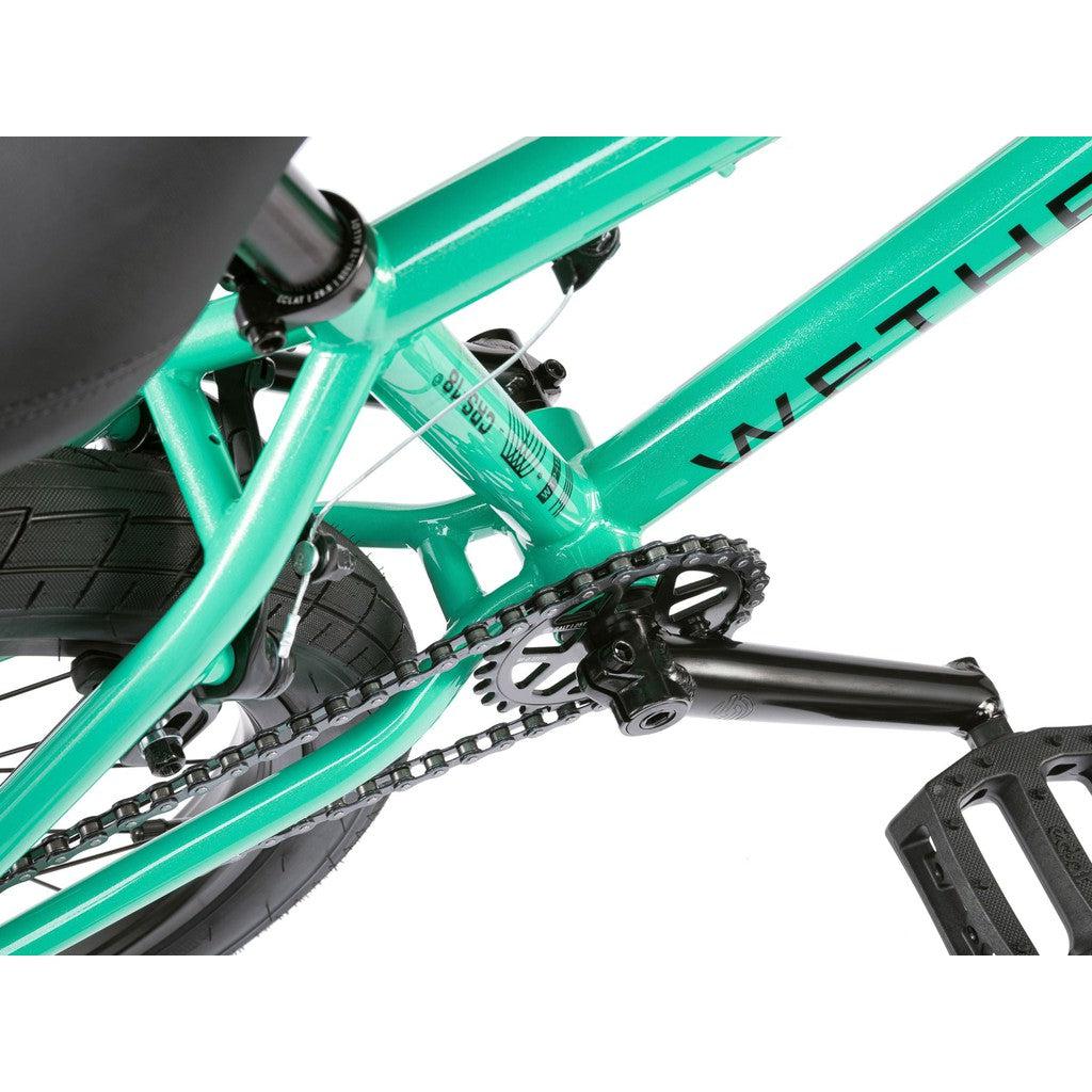 Close-up of a Wethepeople CRS FS 18 Inch BMX bike in teal, showcasing the pedal, chain, and rear wheel with a sleek Salt rotor setup.