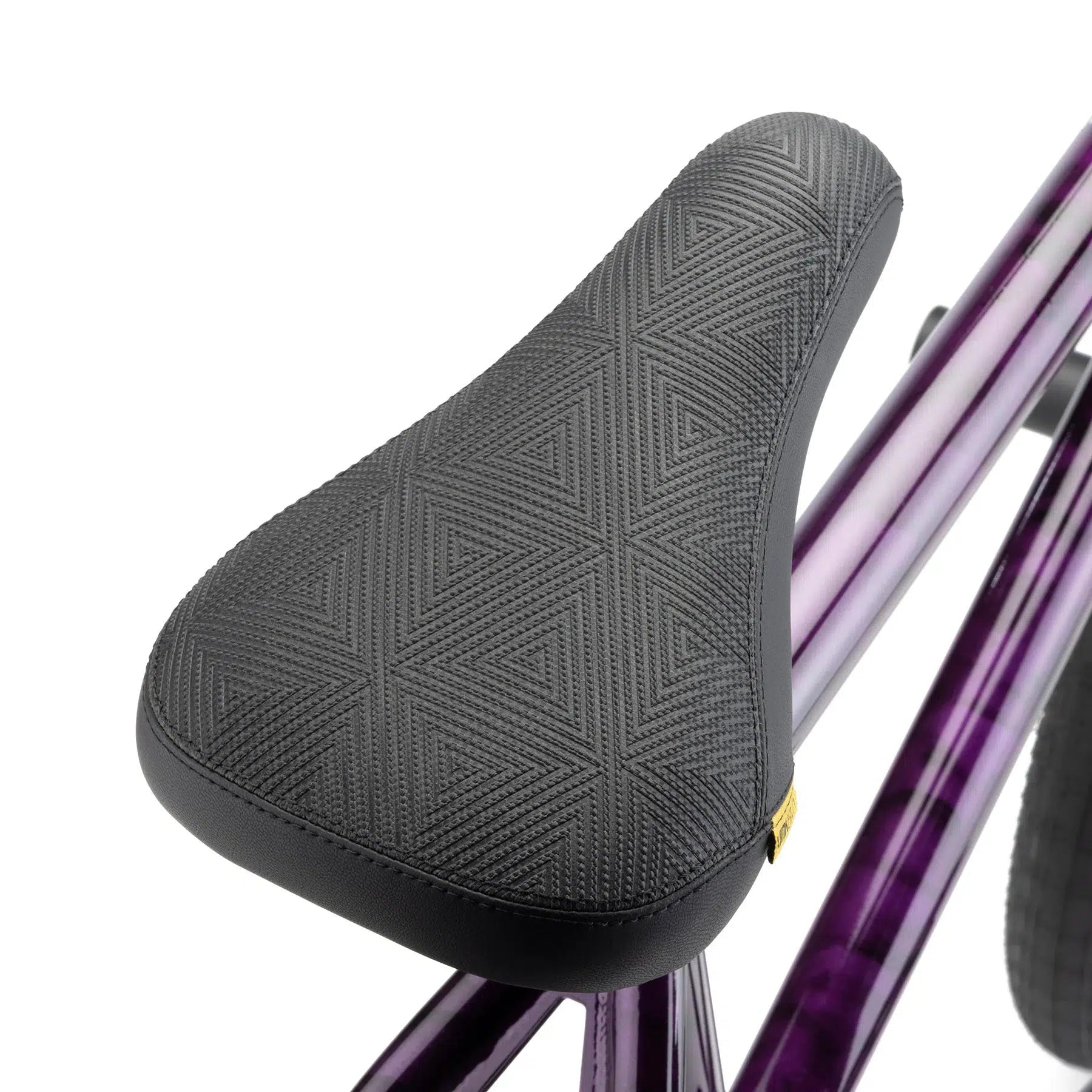 Close-up image of a bicycle seat with a textured black surface, mounted on a metallic purple Kink Downside 20 Inch Bike frame. The modern geometry and high-quality aftermarket parts make it stand out.