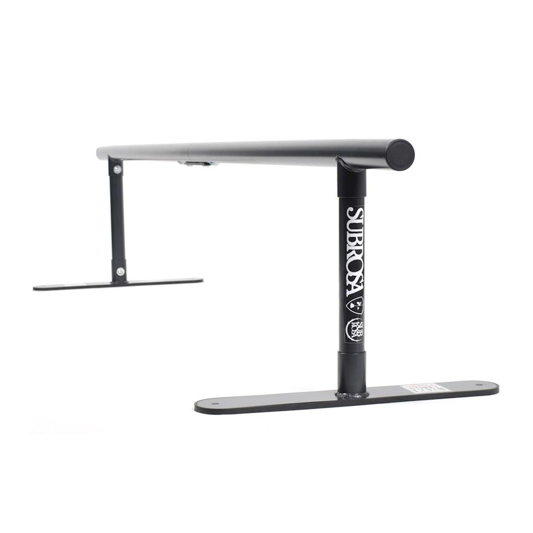 The Subrosa Street Rail is a black metal BMX rail with a logo on the vertical support, offering exceptional grindability. Its sleek design makes it easily portable for diverse skate park adventures.