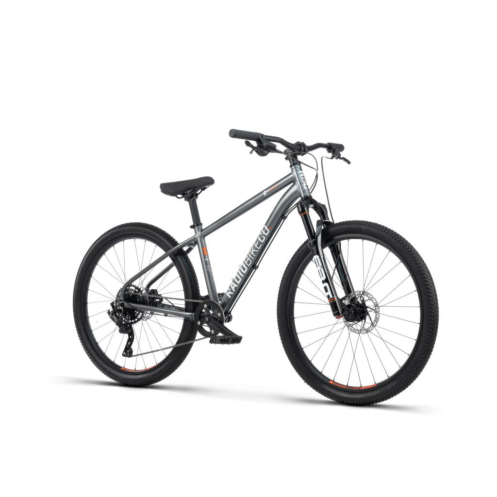 The Radio 26 Inch Zuma Sus Bike is a black and gray mountain bike designed for off-road cycling, equipped with disc brakes, front suspension, and knobby tires. It features a lightweight alloy frame adorned with "2.0" on the front fork and "ARROYO" on the frame, making it a perfect kid-sized MTB bike for young adventurers.