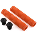 Two Alienation Backlash V2 grips in orange, featuring black bar end plugs, are made from a proprietary rubber formula and displayed on a sleek white background.