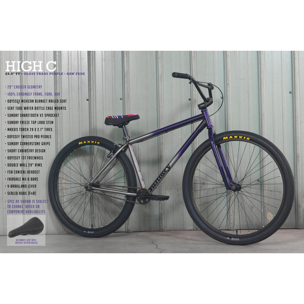 A Sunday High C 29 Inch Bike leans against a corrugated metal wall, featuring a purple chromoly frame, black tires with yellow "Maxxis" branding, and a simple seat for a sleek ride.