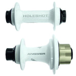 Two white bicycle hubs are displayed. One has "HOLESHOT" printed on it with black caps, while the other is part of the Answer Holeshot Pro Hub Set 36H. This hub features a gold-colored component on one end and boasts precision sealed Japanese bearings and CNC machined aluminum construction.