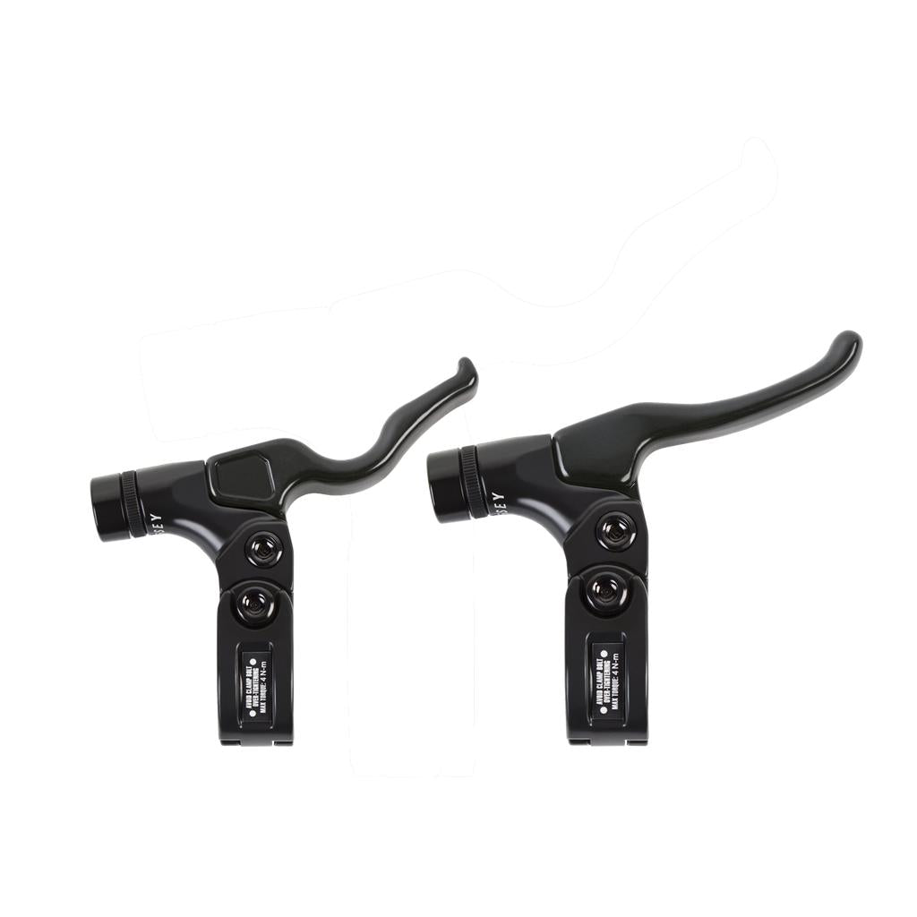 Set against a pristine white backdrop, two black brake levers from the Odyssey M2 Monolever Lever Kit shine, hinting at their advanced dual cable system designed for precision and reliability in biking adventures.