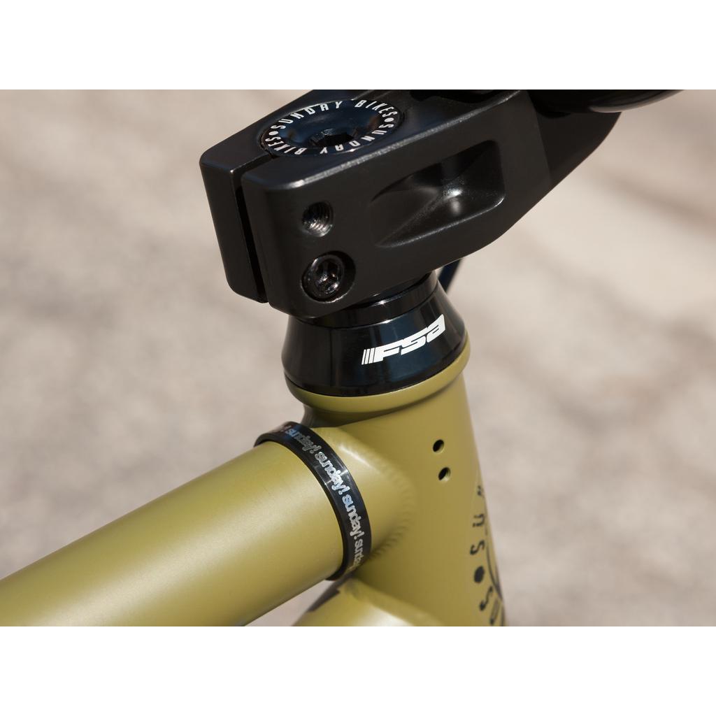 Close-up of a Sunday Wave Length 20 Inch (Gary Young) bike's front headset and stem with an FSA logo. The matte olive green chromoly frame features a visible toptube, highlighted by premium Odyssey parts.