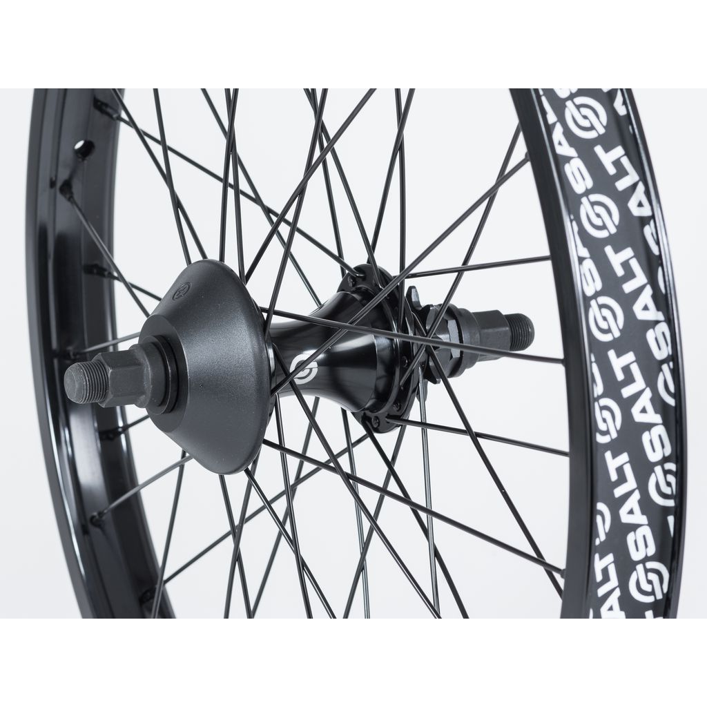 Close-up image of a Salt EX Cassette Rear Wheel with black spokes and bolts on a black single wall rim featuring repeating "SALT" branding.