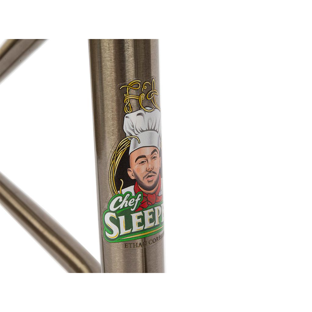 Close-up of a metal rod with a cartoon chef and the text "Chef Sleepy" above "Fit Bike Co Sleeper (Ethan Corriere) Frame.