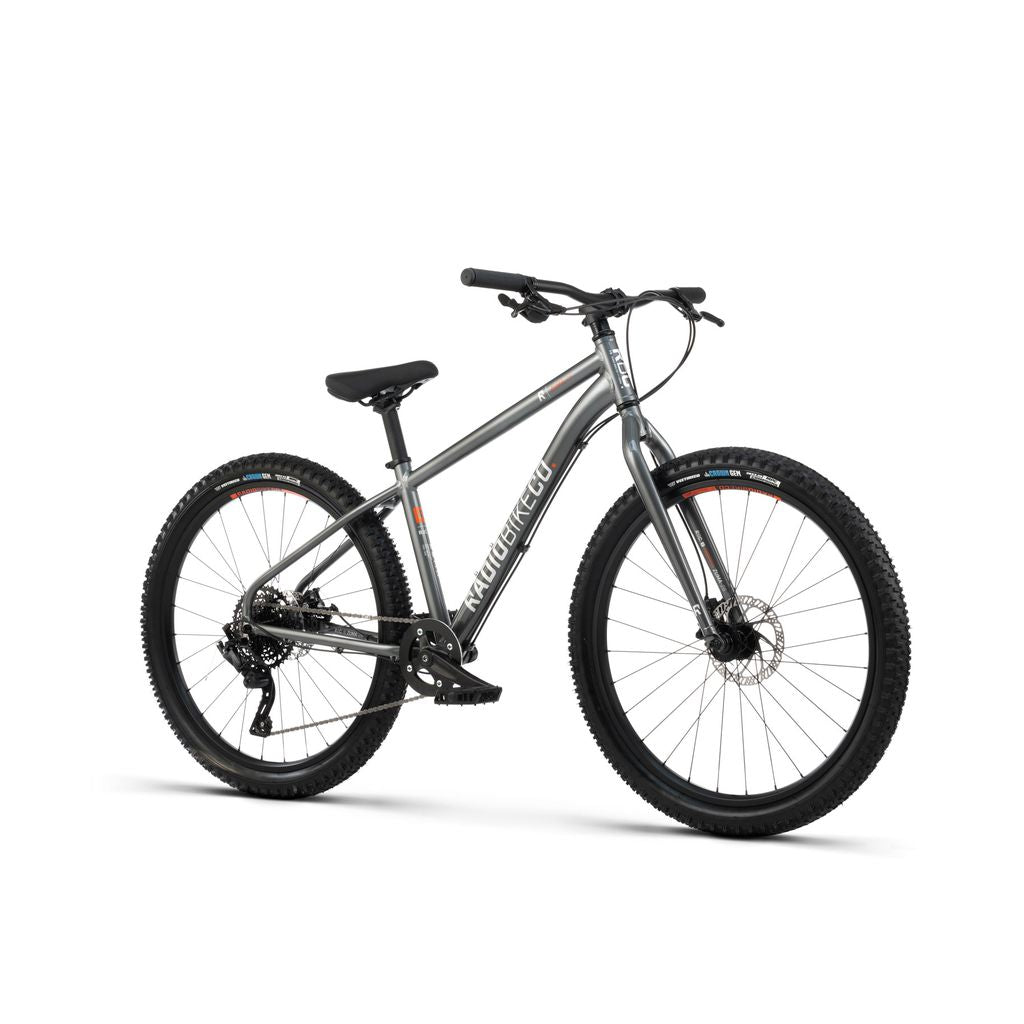 Presenting the Radio 26 Inch Zuma Bike: A sleek silver mountain bike highlighting black tires, a black seat, and black handlebars. The bike is seen from a slight angle and showcases its slanted crossbar design. It comes equipped with gears and disc brakes, featuring a lightweight alloy frame for optimal performance.